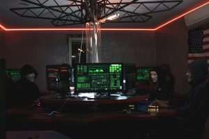Home Team of hackers with Guy Fawkes masks coding in a dark room with computers.